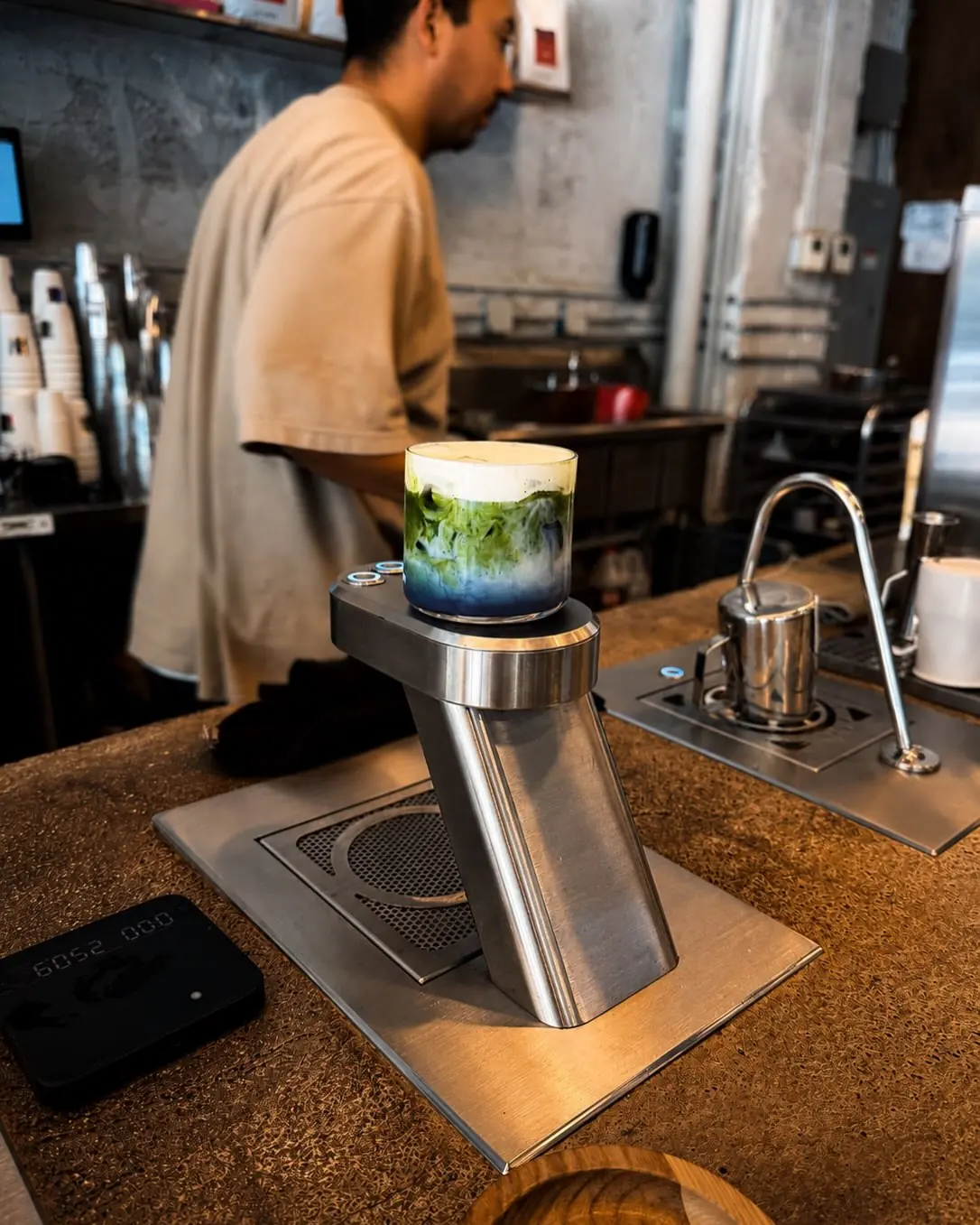 A barista behind the concrete bar